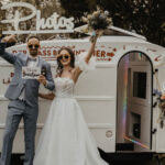 jubelndes Brautpaar vor dekoriertem Caravan